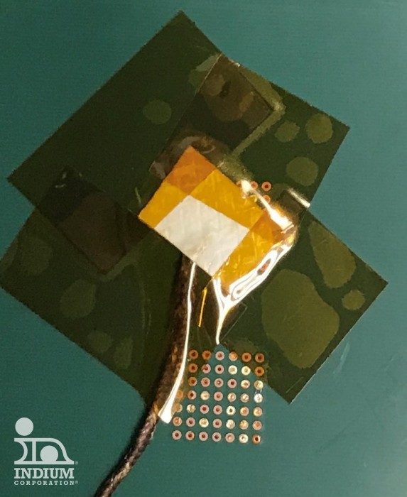 A thermocouple attached to the bottom side of a component using aluminum tape secured with a window-pane of Kapton tape