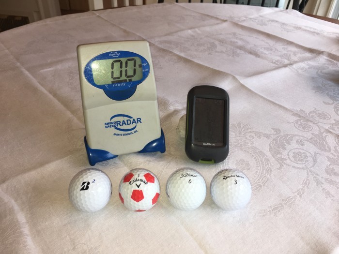 Figure 1. The four golf balls  I tested, my swing speed radar unit, and my GPS unit.