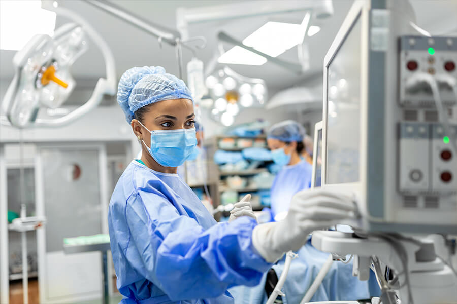 A surgeon in scrubs and a mask skillfully guides medical-grade soldering tools in a hospital operating room.