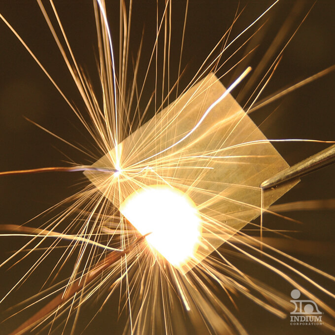 Close-up of bright sparks flying from metal being cut with an electric tool, surrounded by thin wires.