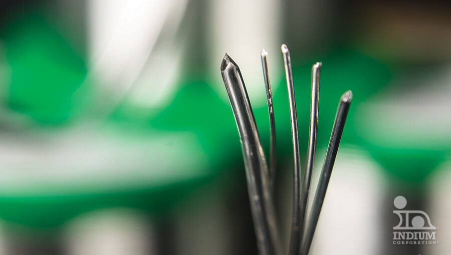 Close-up of several industrial needles with a green blurred background.