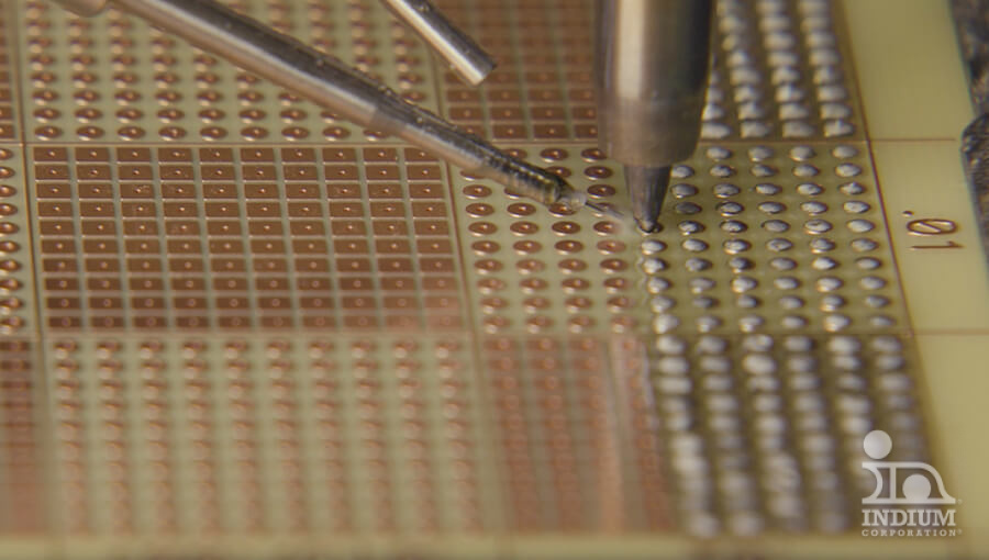 Close-up of a circuit board with tools placing components, highlighting intricate electronic assembly.