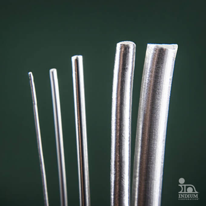 Five silver wires of varying thicknesses are aligned vertically against a dark green background.