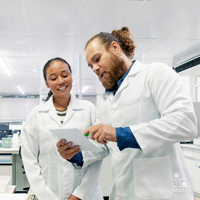 Two scientists in lab coats, synced in pattern, discuss a document in the modern laboratory setting, navigating their promising careers with precision.