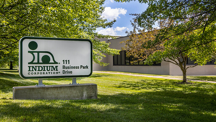 Sign for Indium Corporation at 111 Business Park Drive, with trees and a building in the background.