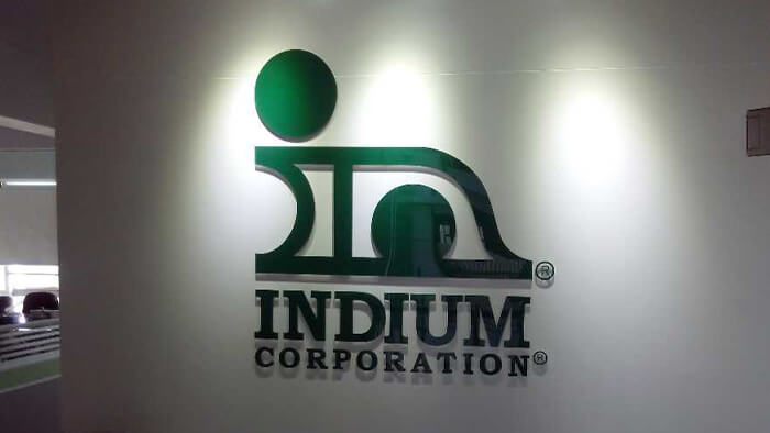 Logo of Indium Corporation with a stylized green design on a white wall.