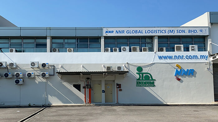 Exterior of a logistics company building with air conditioning units and signage on the walls.