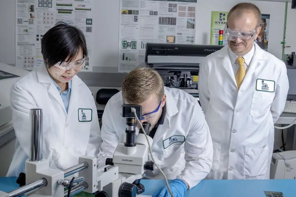 3 scientists looking under a microscope